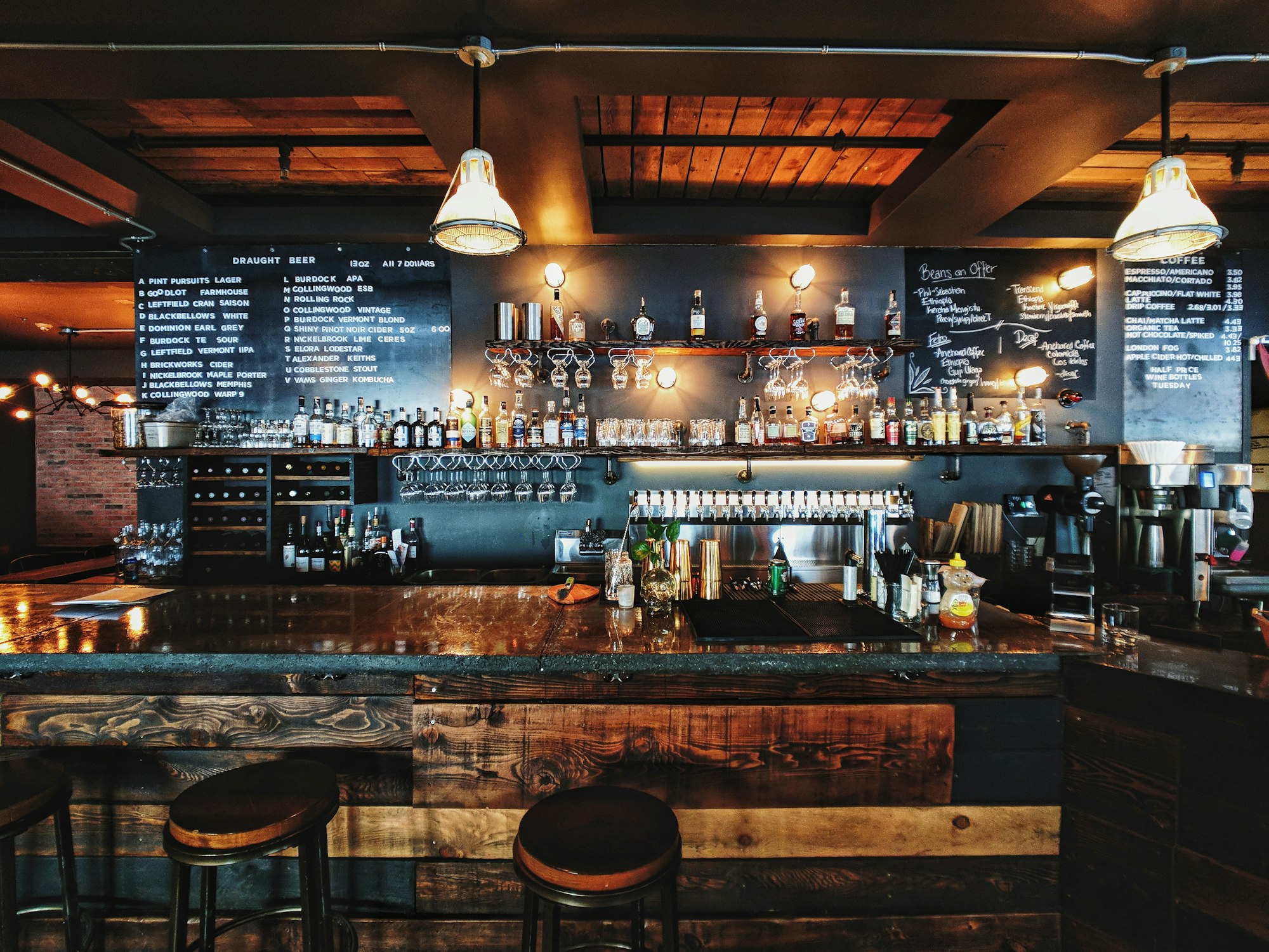 Interior de un bar-cafetería local, con barra de madera y menú escrito a mano